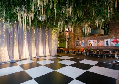 Custom black and white dance floor with hanging greenery and café lights set for a wedding reception at the Gastropub at ICON in downtown Sioux Falls.