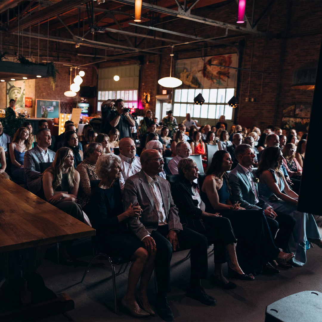 Audience seated in an industrial-style hall listening to a speaker during a corporate event at ICON in downtown Sioux Falls.